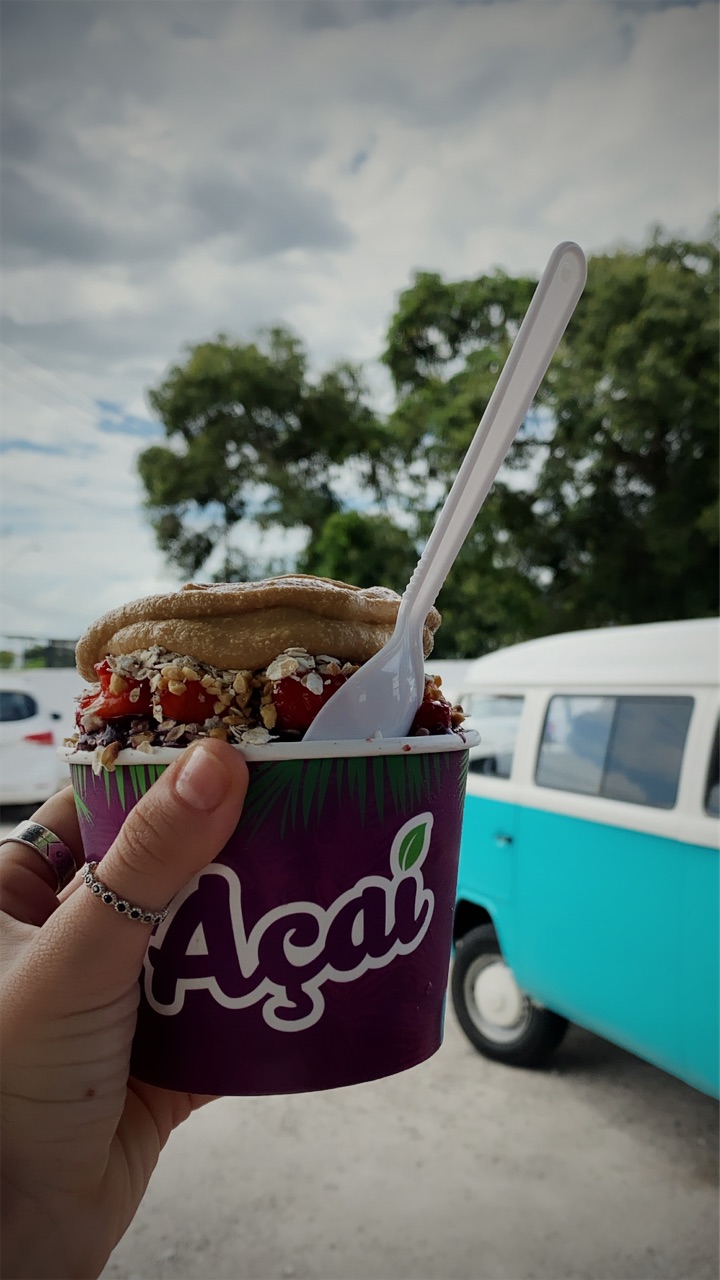 An açaí cup held up in front of a camper van