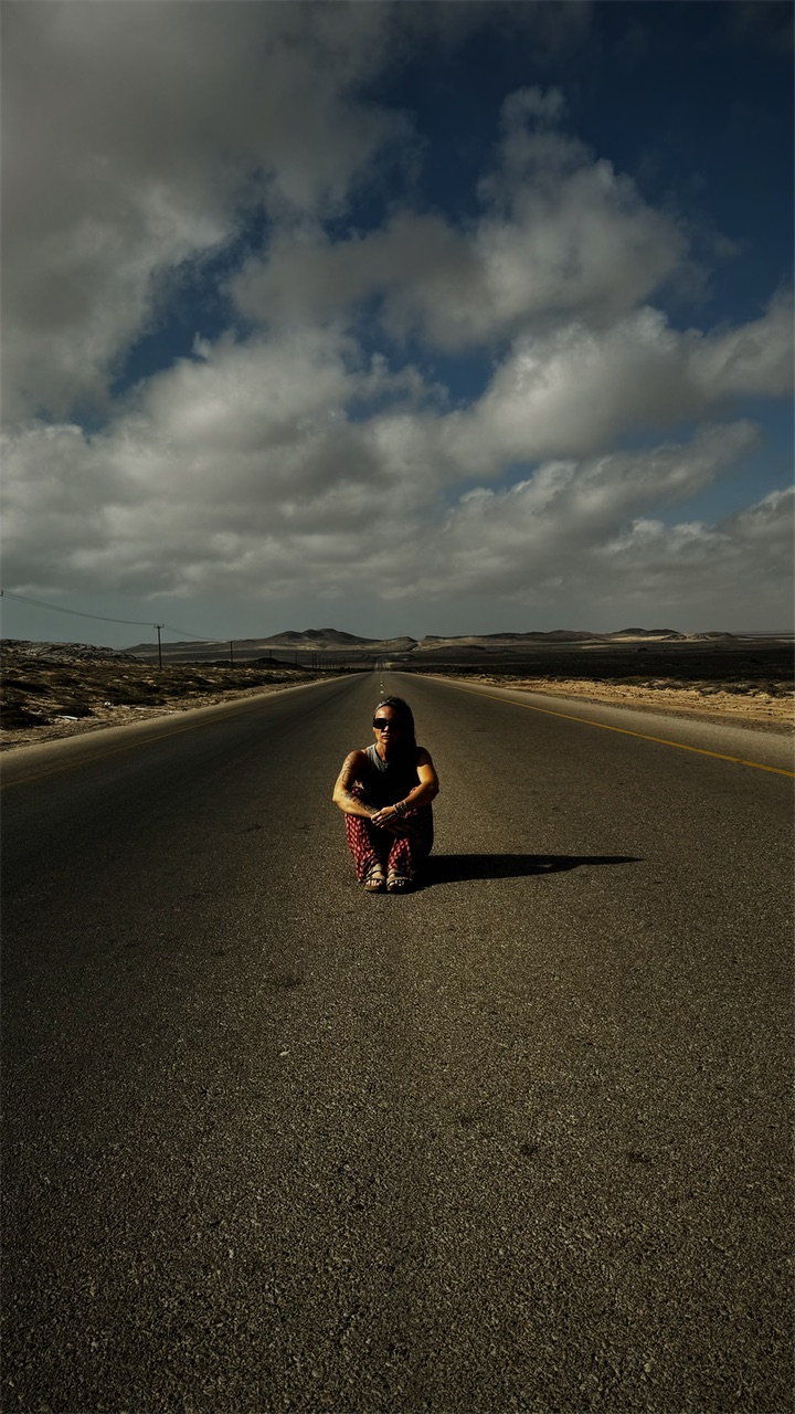 Cristiana sitting in the middle of an empty desert road