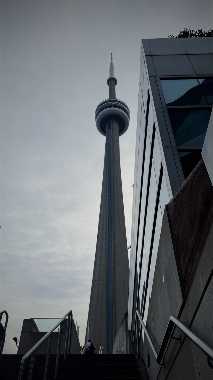 The CN Tower seen from a stairway beside a glass building
