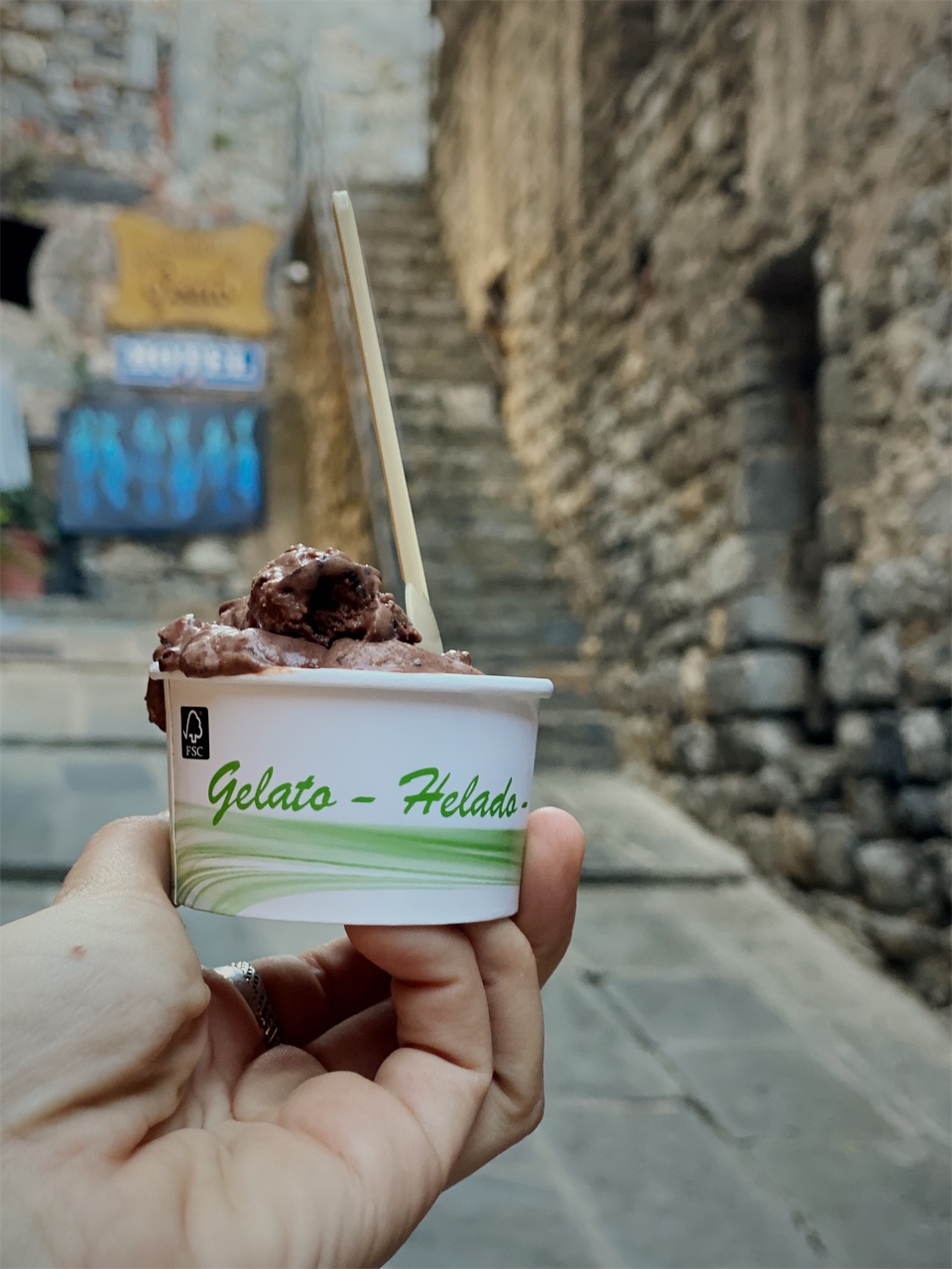A cup of chocolate gelato in a narrow stone alley